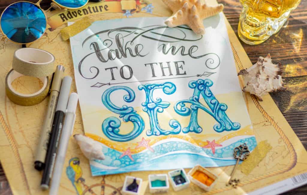 The Best Pens And Markers For Scrapbooking - The Creative Folk Scrapbooking pens and markers arranged beside patterned paper and photo layouts
