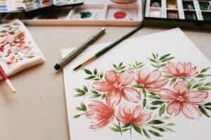 The Best Gifts For Watercolor Artists - The Creative Folk Watercolor floral painting with brushes and a paint palette on a desk