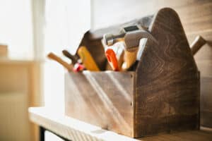 Best Wood Scribes For Woodworking - The Creative Folk Wooden toolbox holding a hammer, chisels and hand tools