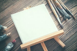 Best Tabletop Easels For Painting - The Creative Folk Easel with a canvas, paint tubes and brushes on a wooden table