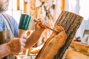 man using carver's mallet to chisel wood